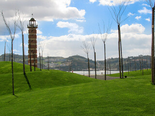 Lisbon, Portugal - Belem Lighthouse, a small red brick and concrete building near the waterfront, surrounded by bare trees under a cloudy blue sky.  Image has copy space.