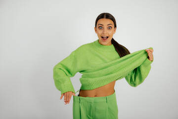 Surprised happy brunette woman in green oversize costume show slim sportive belly, pull down...