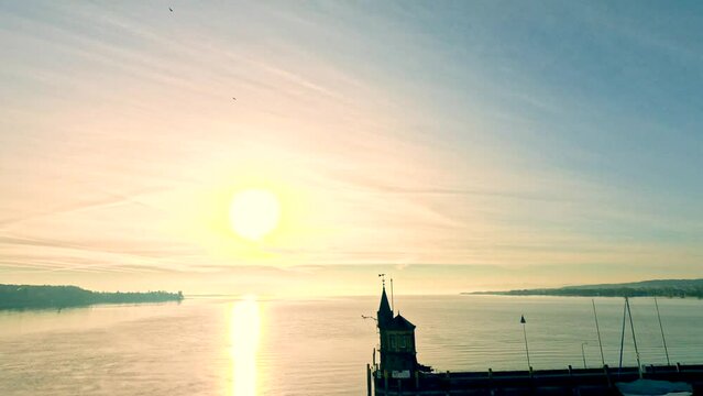 Vorbeiflug an der Imperia Statue und Aufstieg &uuml;ber dem Bodensee bei Sonnenaufgang. Konstanz, Bodensee, Baden-W&uuml;rttemberg, Deutschland, Europa.
