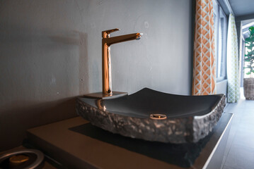 Closeup of fancy modern blank sink with copper faucet by blank wall in bathroom at luxurious hotel,...