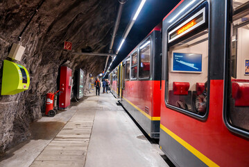 Passengers standing outside train at Jungfrau railway station in mountain tunnel inside Bernese...