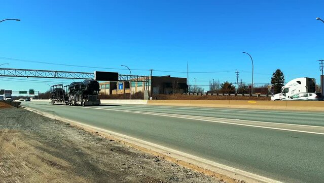 Truck with passenger cars in semi-trailer drives along the freeway exit from the city Dartmouth Canada. Transportation new cars across the country of Canada with the help large truck semi-trailers. 