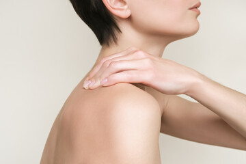 Obraz na płótnie Canvas a woman feels pain in her neck and back and massages her deltoid muscle and shoulders