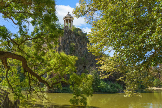 Buttes Chaumont Park in Paris, France. Lake in the park and Sibyl temple on the hill.