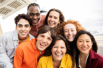 Multiracial group of seven young millennial friends taking selfie portrait together outside