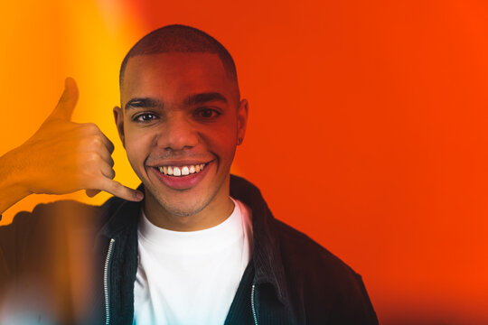Smiling African American man hand gesturing pretending to be on the phone. High quality photo