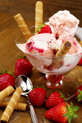 Coppa di gelato al mandecato alla fragola con fragole e cannoli di wafer al cioccolato