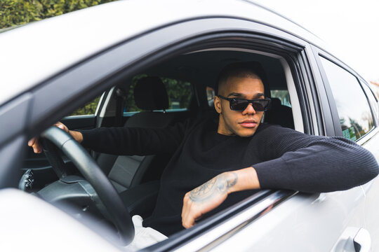 African American man in sunglasses leaning out of a car window and looking away. High quality photo