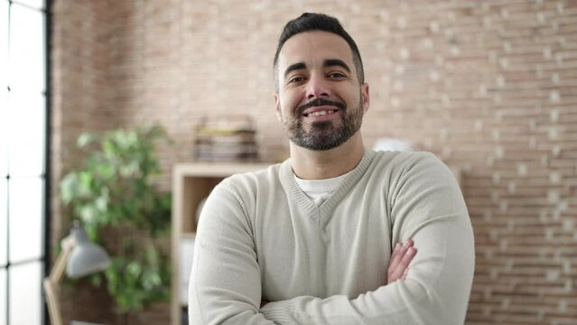 Young hispanic man business worker smiling confident standing with arms crossed gesture at office