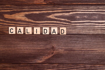 Calidad, quality spanish word, lettering on wooden background