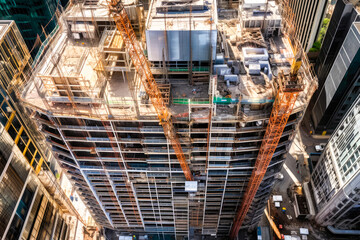 Fototapeta premium Top down view of skyscraper construction, drone aerial point of view. Cranes and other construction equipment. High quality generative ai