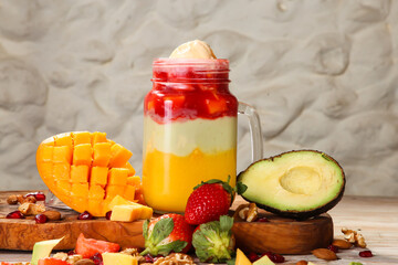 Strawberry, mango and avocado juice with pomegranate seeds, walnut, almond and cashew served in jar isolated on background top view of healthy morning drink