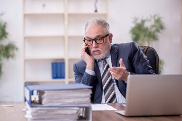 Fototapeta premium Old male employee and too much work at workplace