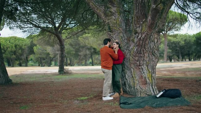 Loving couple enjoy weekend on nature. Happy tourists standing hugging near tree