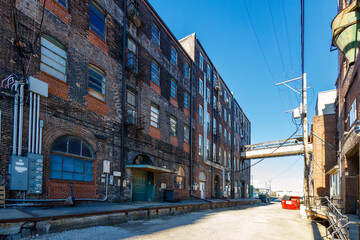 view from the alley of an old warehouse from the 1800's with many windows on a sunny day