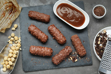 Tasty chocolate bars with caramel and nuts on light grey table, flat lay