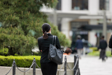 オフィス街を電話をしながら歩くスーツ姿の若い女性