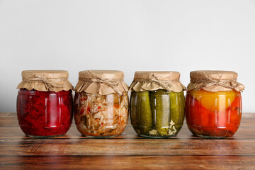 Jars with different preserved vegetables on wooden table