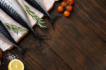Raw mackerel, tomatoes and rosemary on wooden table, flat lay. Space for text