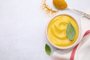 Tasty curry sauce, powder and basil leaves on light table, flat lay. Space for text