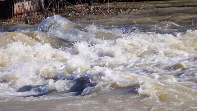 Close up slow motion video of a small river that is flooded by melting snow and ice during a spring thaw 
