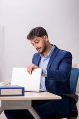 Young male employee sitting at workplace