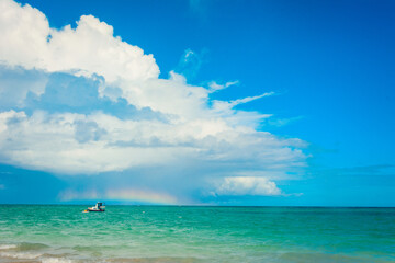 A rainbow over the sea on a sunny day with blue sky