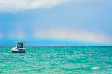 Snapshot of a rainbow over the sea on a sunny day with blue sky