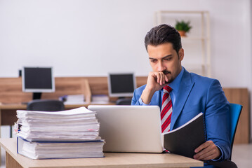 Young male employee unhappy with excessive work at workplace
