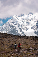 Obraz premium Young hikers on the ausangate circuit in front of the snow-covered peak, Ausangate 6384m, Cordillera Vilcanota, Peru, South America