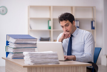 Naklejka premium Young male employee and too much work in the office