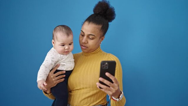 Mother and son hugging each other using smartphone over isolated blue background