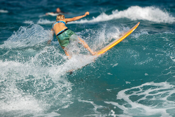 Caucasian female surfer colourful swimmers surfing wave turning surfboard ocean blue