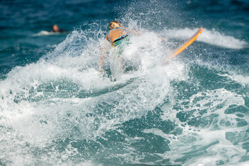 Caucasian female surfer colourful swimmers surfing wave turning surfboard ocean blue