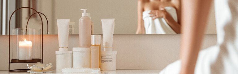 Charming woman sitting near cosmetic products in spa salon