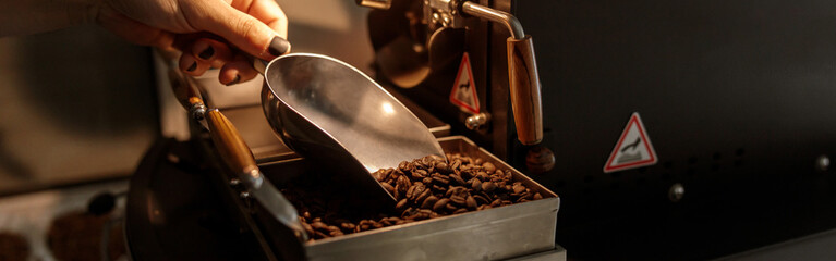 Male hand holding metal scoop with coffee beans
