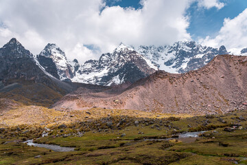 Photos of the tranquil turquoise lake and admiring the snow-capped Ausangate mountain peaks on a sunny day in Peru.