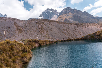 Naklejka premium Photos of the tranquil turquoise lake and admiring the snow-capped Ausangate mountain peaks on a sunny day in Peru.