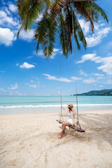 Fototapeta na wymiar Young woman traveler enjoying on the swing at beautiful tropical white sand beach, Summer vacation and Travel concept