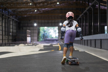 asian child skater or kid girl fun playing skateboard or start ride surf skate in indoor pump track skate park by extreme sports surfing to wears helmet elbow pads wrist knee guard for body safety