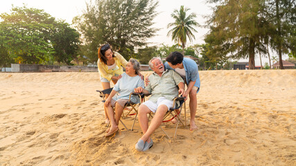 Fototapeta na wymiar Happy Asian family travel ocean on summer holiday vacation. Adult couple and aging parents enjoy and fun outdoor activity lifestyle resting and talking together at tropical island beach at sunset.