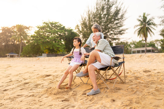Group of Happy Multi-Generation Asian family enjoy and fun outdoor activity lifestyle resting and playing together at tropical island beach during travel ocean at sunset on summer holiday vacation.