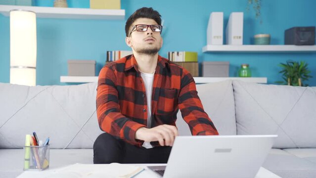 Young man working on laptop resentful of failure. Seeing his failure on the laptop, the young man is frustrated and angry.