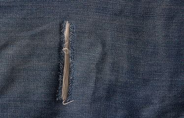 Close-up photo of torn blue jeans. Ripped denim blue cloth background.