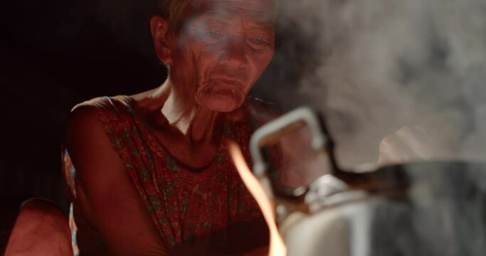 Slow motion Asian rural life at night which is a poor husband and wife, farmers and employees in the farm, cooking using a stove with firewood, boiling steam and smoke from firewood. 