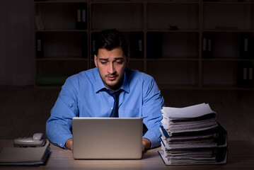 Young male employee working late in the office