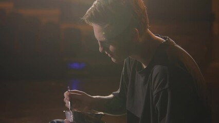 Professional ballet dancer in training suit sits on dramatic theater stage eating delivery dinner. Man has break before theatrical performance. Male performer rests during choreography rehearsal.