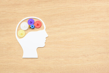 Creative idea / critical thinking process / human imagination concept : Color gears cog wheels in human head on wooden background with blank space, depicts brain improvement with new idea generation