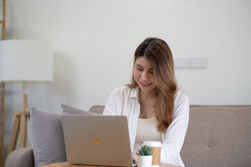 Fototapeta premium Business woman working from home. work online on laptop. Asian businesswoman working on sofa online business with social distancing laptop online meeting.