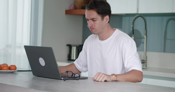 Aggressive man, dissatisfied with results of working at laptop, take off glasses and aggressively beats his fist on table, experiencing irritability and emotional stress. Outburst of rage during work.